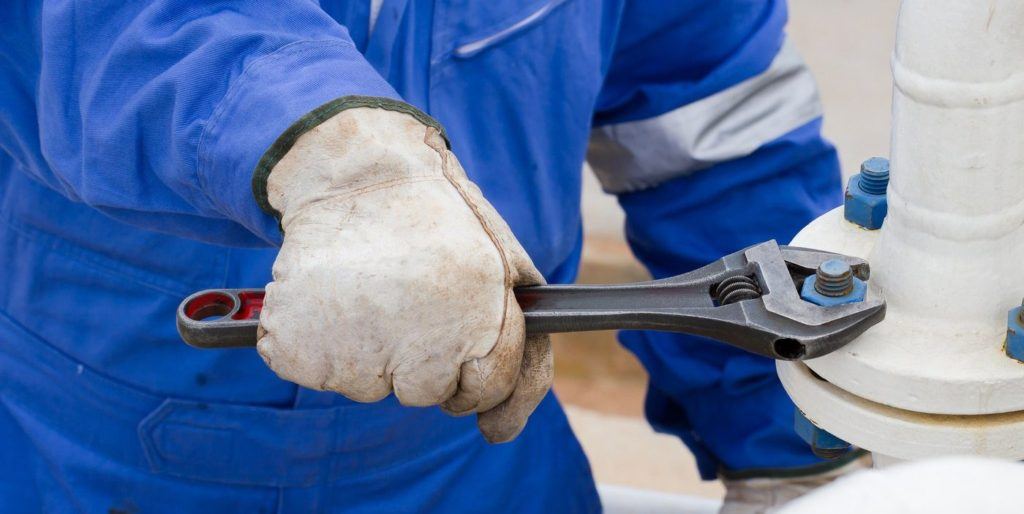 Close-up image of human hand fixing and stop leak flange by wrench in oil and gas process