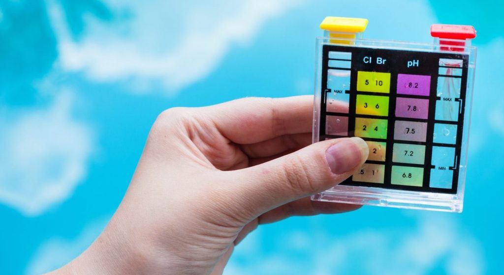 checking pH level in blue outdoor pool by chemical tester