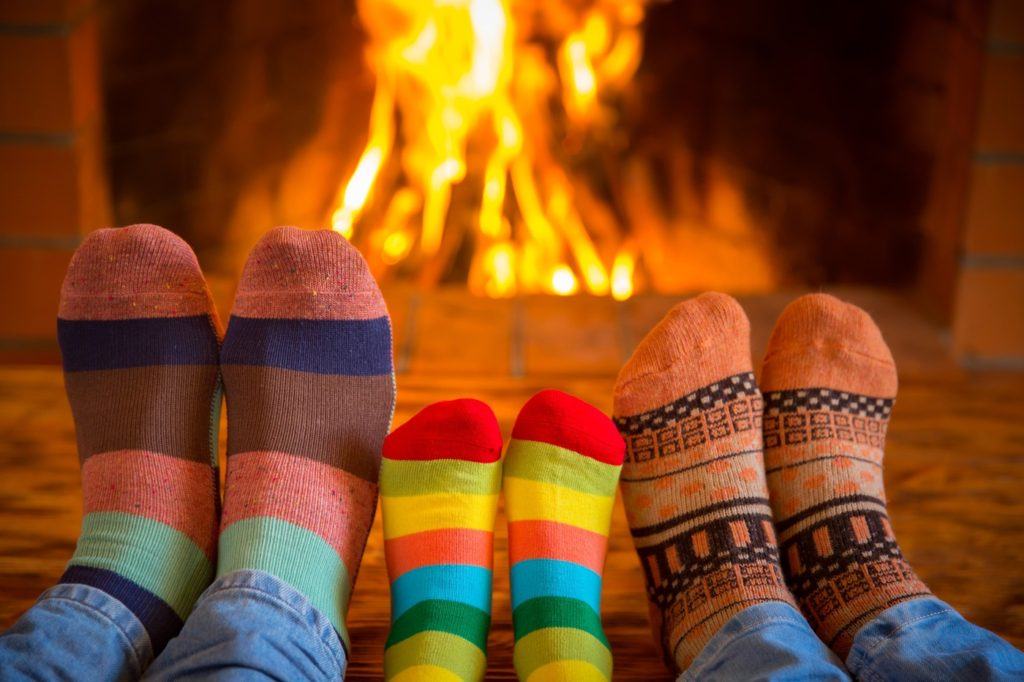 Family relaxing at home. Feet in Christmas socks near fireplace. Winter holiday concept