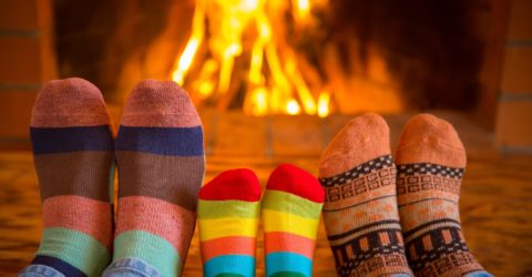 Family relaxing at home. Feet in Christmas socks near fireplace. Winter holiday concept