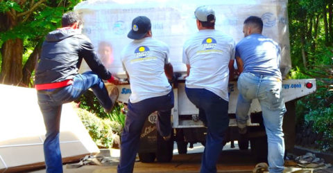 Four crew members unloading hot tub from flat bed truck.