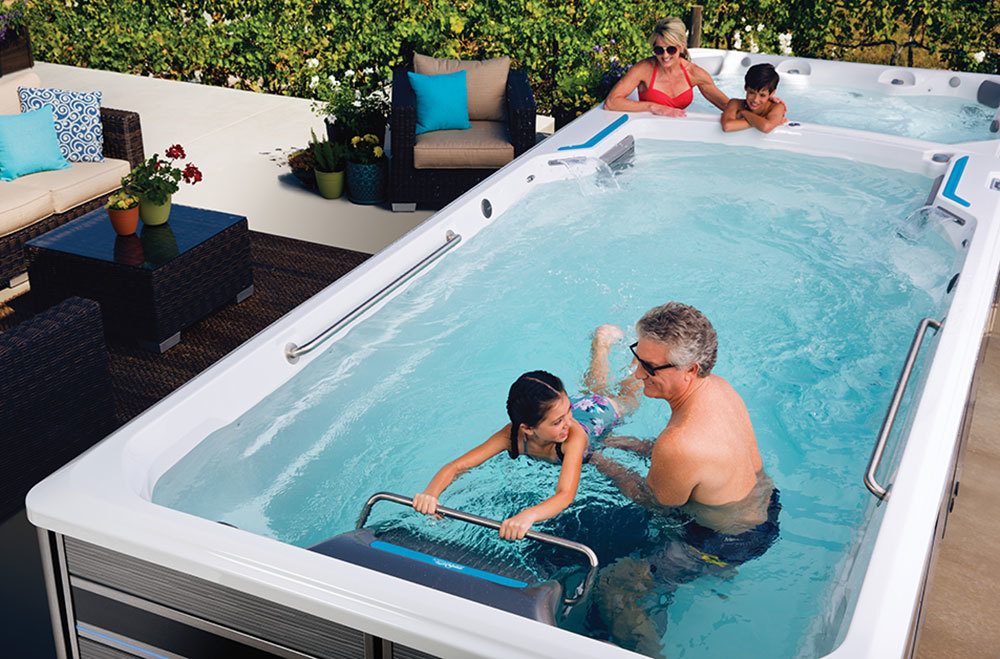 family of four swimming and lounging in an endless pool swim spa