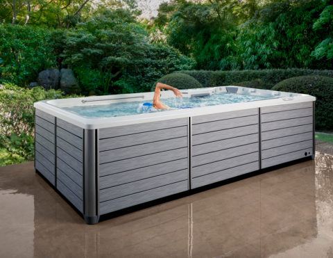 man swimming in the R500 swim spa on backyard patio