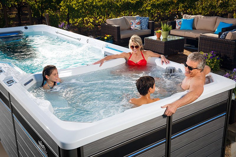 father, mother, and two children in the spa part of a endless pool swim spa