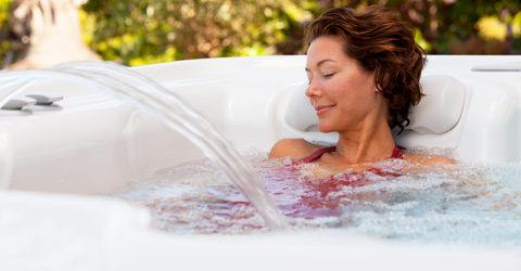 woman relaxing with eyes closed in backyard hot tub