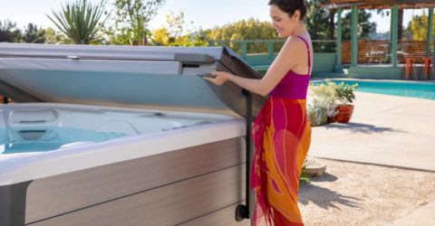 woman in a sarong lifting hot tub cover from spa