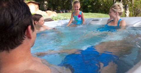 family of four enjoying hot tub on sunny day