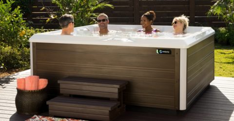 four people in a full size hot tub in backyard