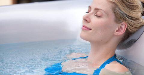 young woman relaxing in a hot tub looking very happy