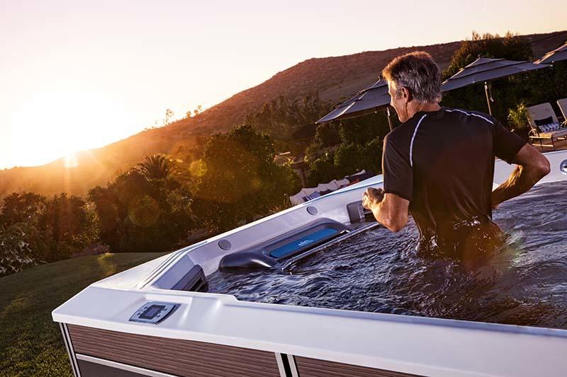 man exercising in a swim space system outside with a sunset