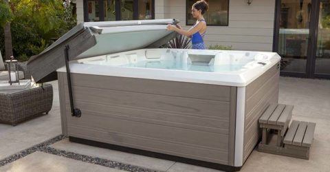 young women in blue bathing suit removing cover off new hot tub in backyard