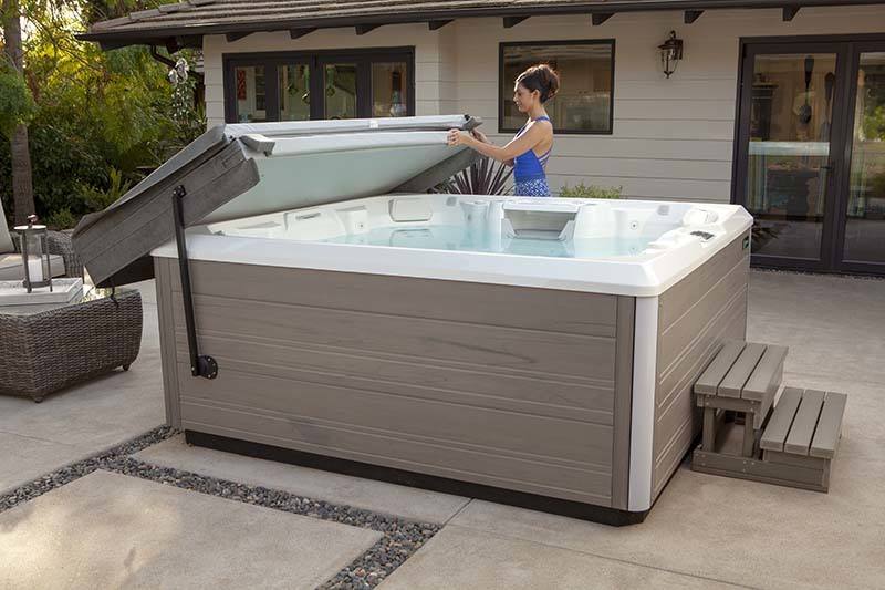 young women in blue bathing suit removing cover off new hot tub in backyard