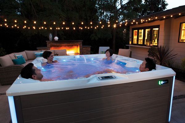 friends relaxing in a hot tub in a backyard on a summer evening