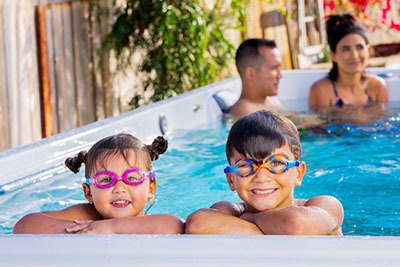 family enjoying their swim spa in their backyard during summer 