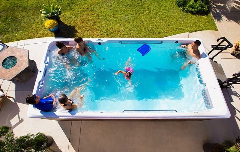 large family enjoying their endless pools swim spa in their backyard during the summer