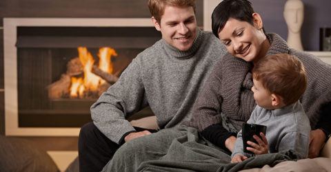 happy family sitting in front of their fire place smiling