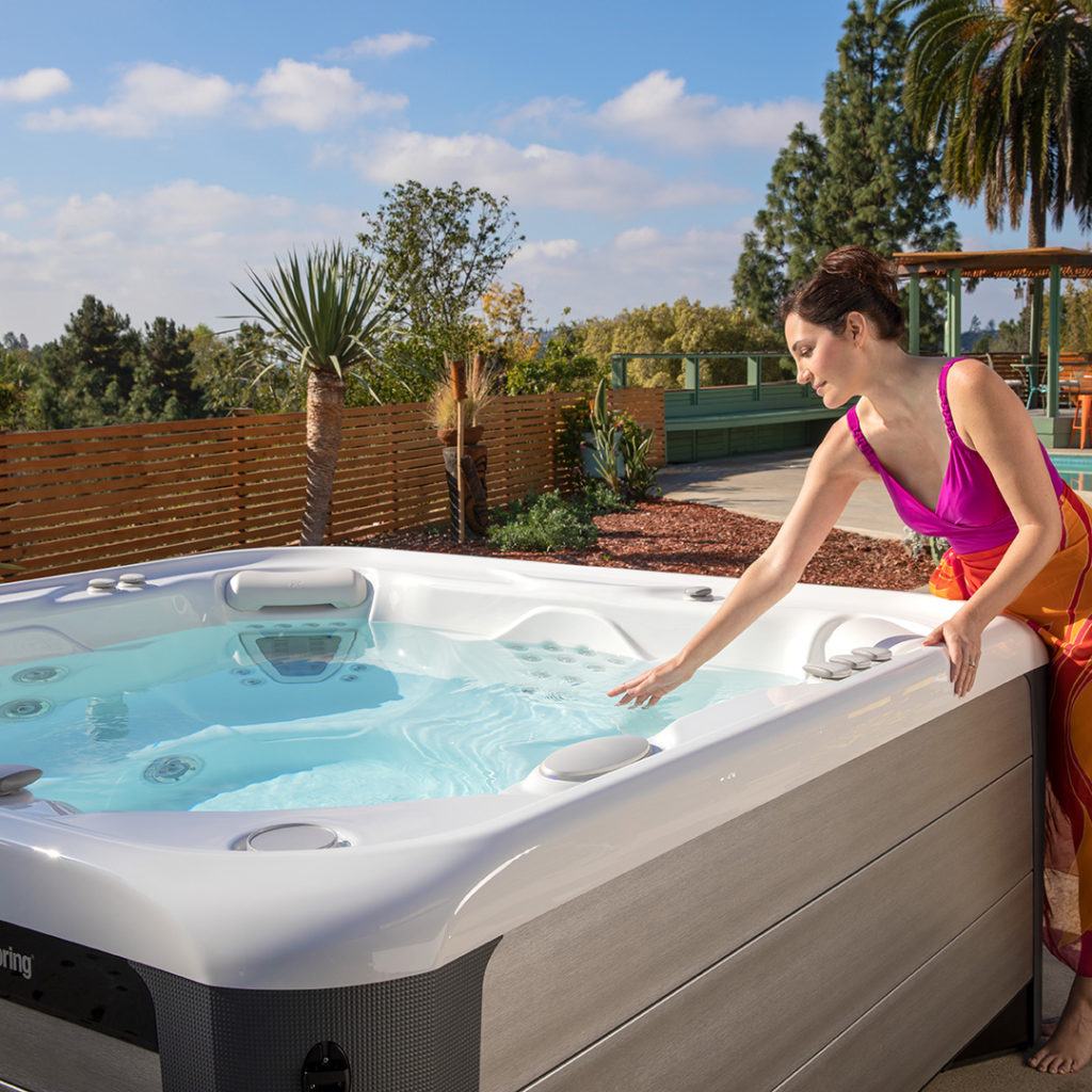 women in backyard looking into her hotsprings spa at brilliantly clean and clear hot tub water