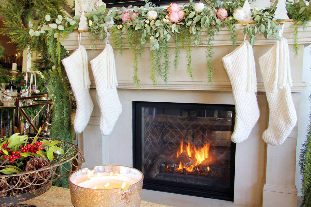 knitted white christmas stockings hanging on a marble stone fireplace mantel