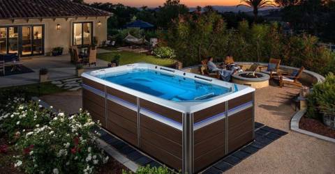 backyard swim spa at dusk with couple around firepit