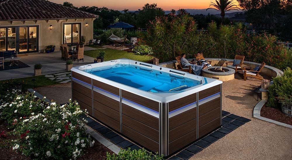 backyard swim spa at dusk with couple around firepit