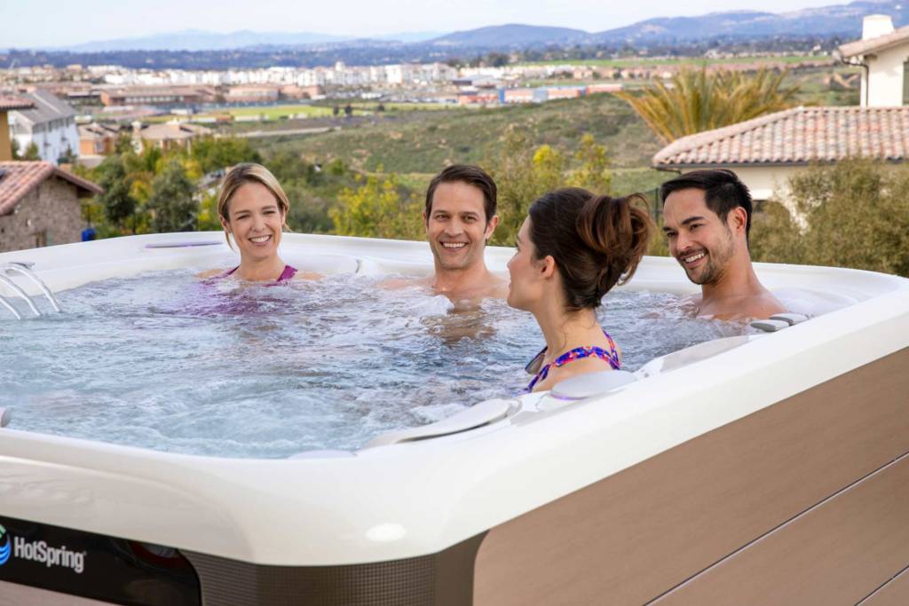 4 young adults enjoying backyard hot tub on a hill with view