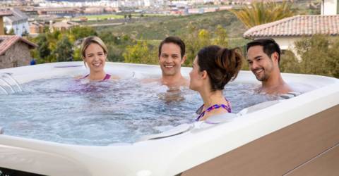 4 young adults enjoying backyard hot tub on a hill with view