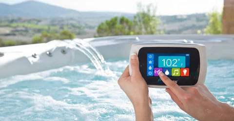 small remote control panel held by woman's hands in hot tub with waterfall