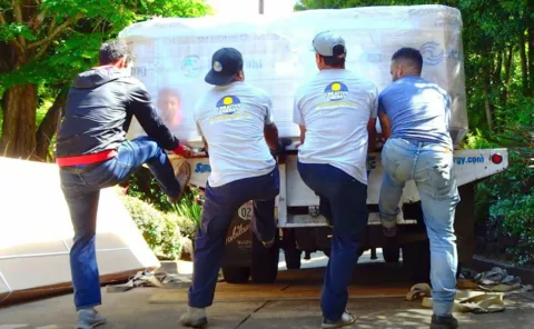 Four men, two wearing Creative Energy shirts offloading a Hot tub in driveway