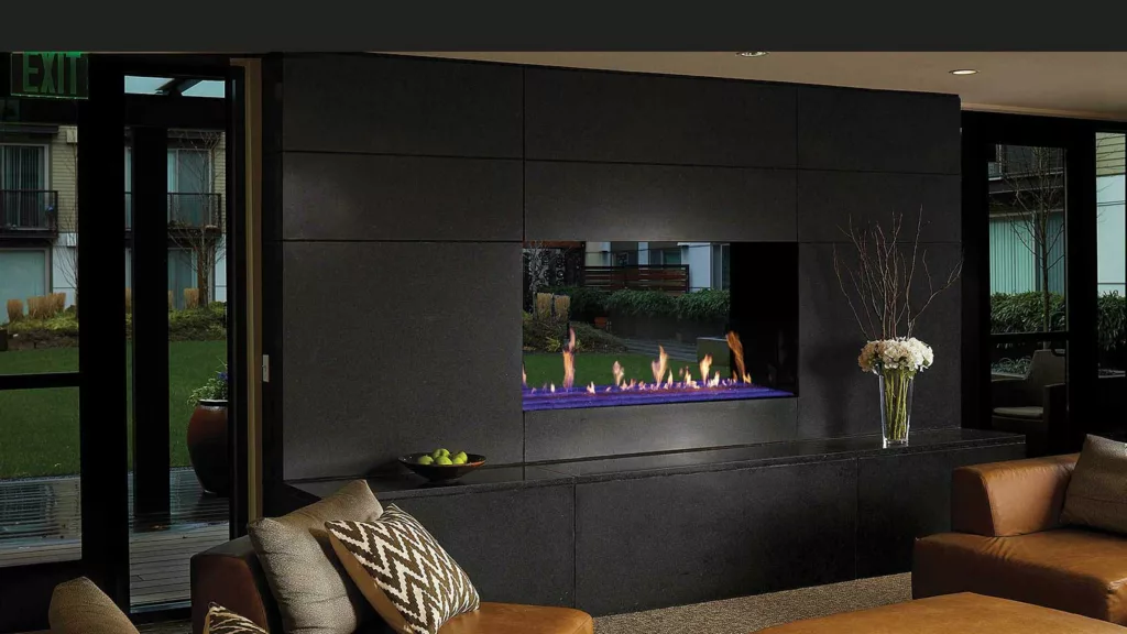 Davinci see-through gas fireplace insert on outside wall in condo complex with greenery seen through fireplace