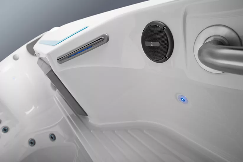 Endless Pools swim spa music system in an off white cabinet near a jet, step and handrail. 