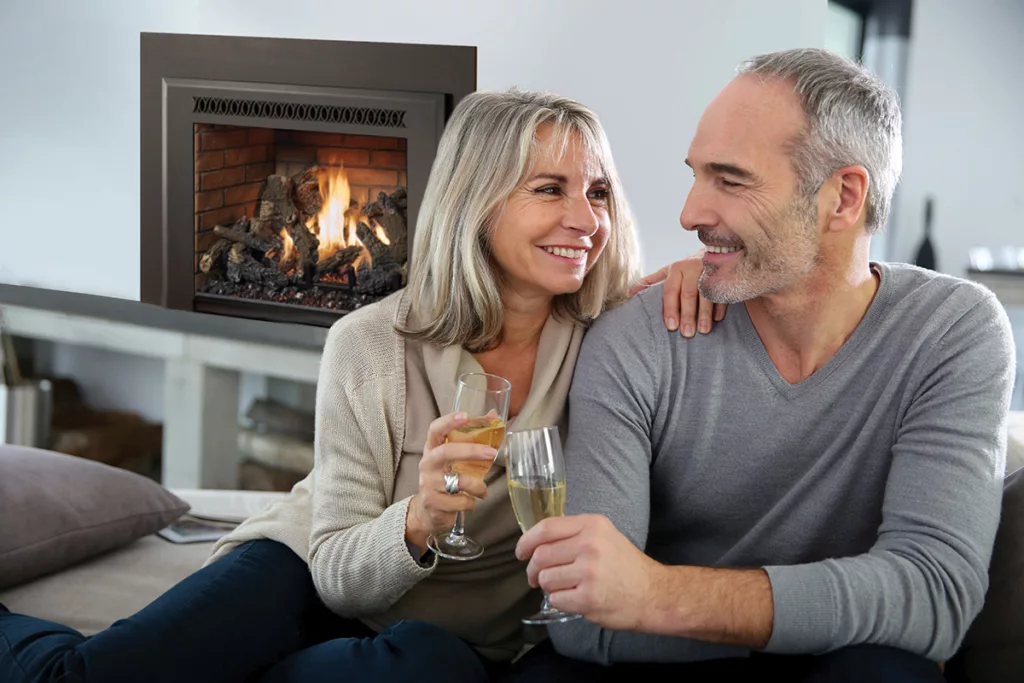 A middle aged couple sitting in their living room in front their fireplace enjoying a romantic evening together