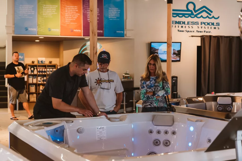 Interior of the Creative Energy San Rafael Showroom featuring multiple Hot Spring hot tub floor models and a friendly employee describing specific features of a spa to two customers