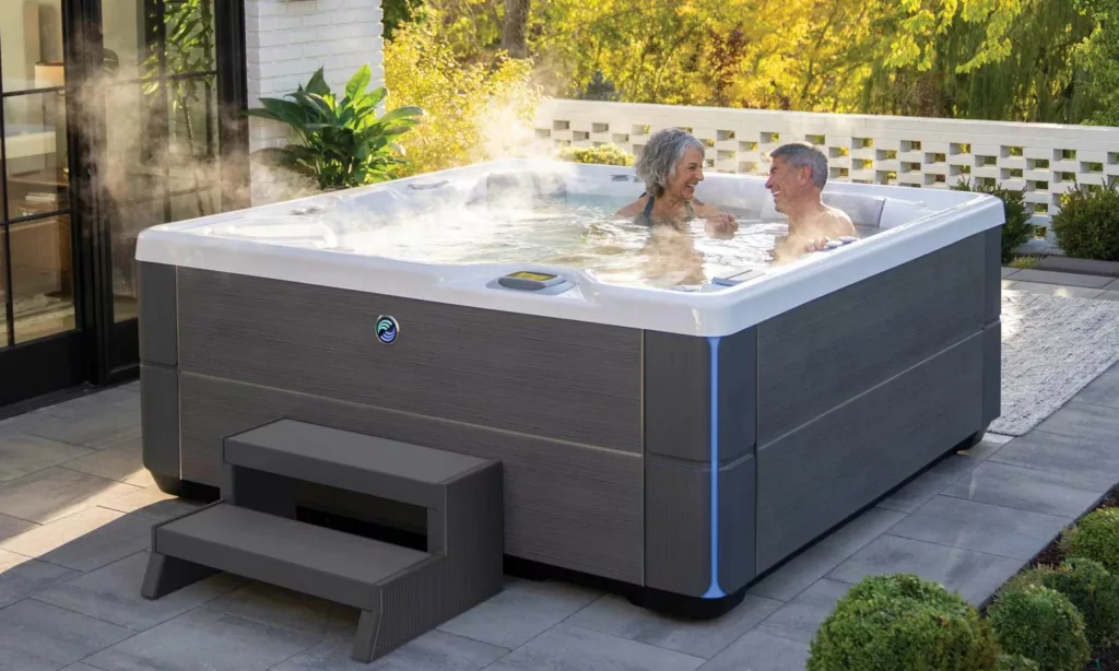 senior couple enjoying Hot Spring hot tub on patio with steam rising.