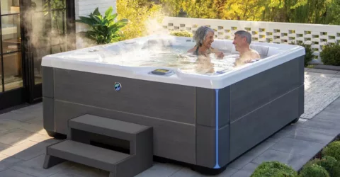 senior couple enjoying Hot Spring hot tub on patio with steam rising.