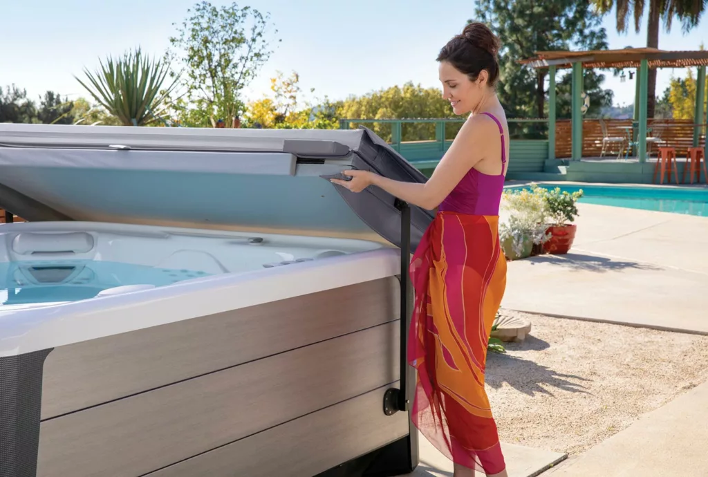 Woman in swimsuit and cover up easily lifting hot tub cover with hydraulic lifter