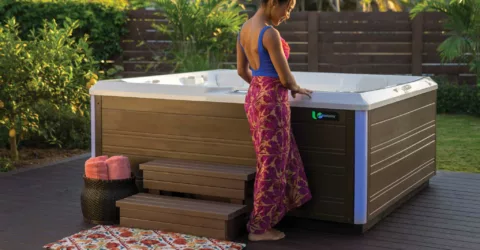 Woman in swimsuit and cover up looking at her hot tub before getting in.