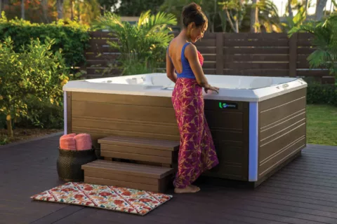 Woman in swimsuit and cover up looking at her hot tub before getting in.