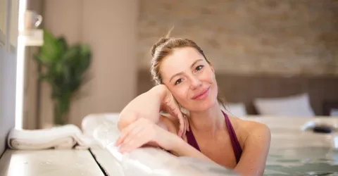 A smiling woman relaxing in an indoor hot tub.