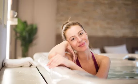A smiling woman relaxing in an indoor hot tub.