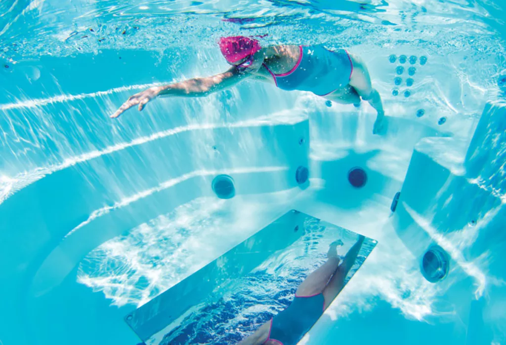 An underwater image of woman swimming with floor mirror in an Endless Pools swim spa.