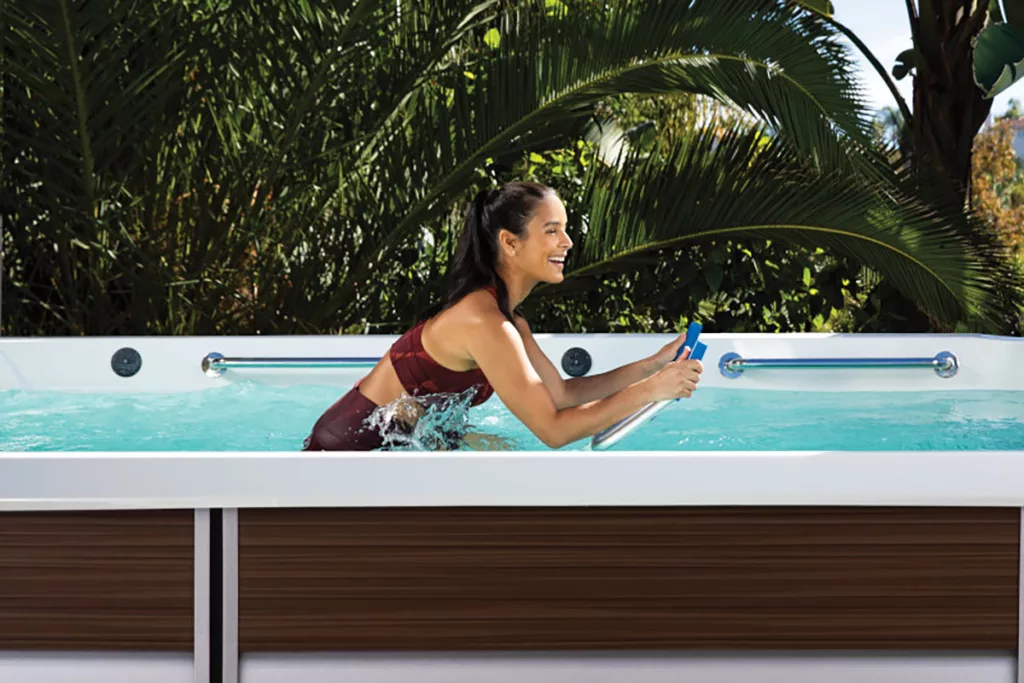 A smiling woman exercises on an Endless Pools aquabike.