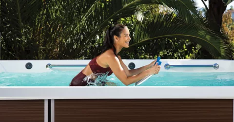 A smiling woman exercises on an Endless Pools aquabike.