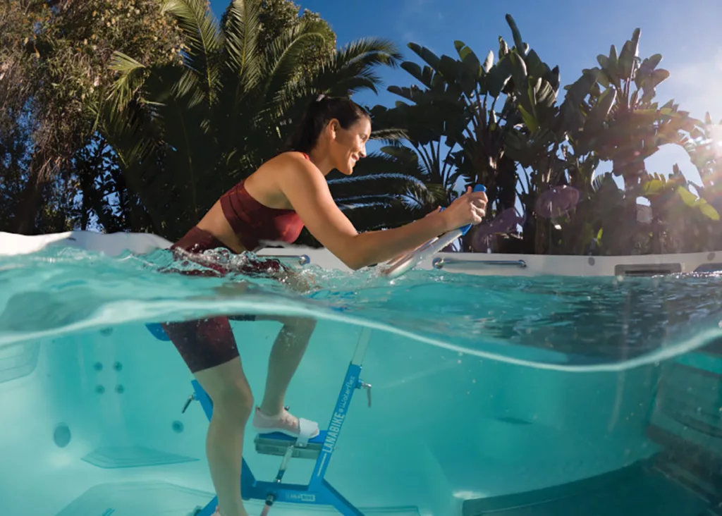 A woman uses an Aquabike in the E550 swim spa.