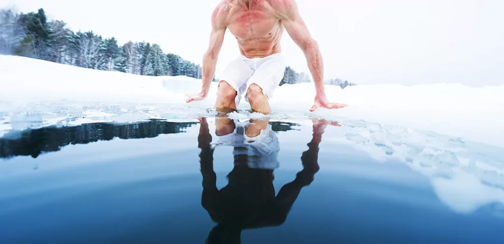 A man takes a cold plunge in an ice hole for the exercise recovery benefits.