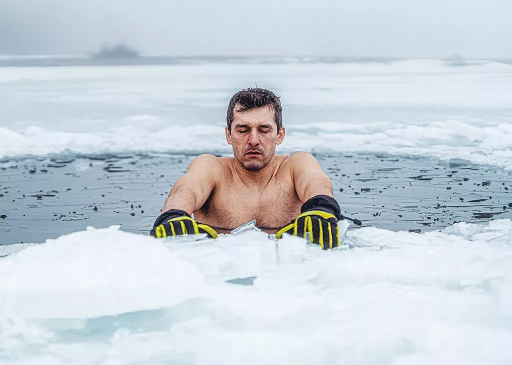 A man takes a cold plunge in an ice hole for the exercise recovery benefits.