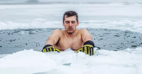 A man takes a cold plunge in an ice hole for the exercise recovery benefits.