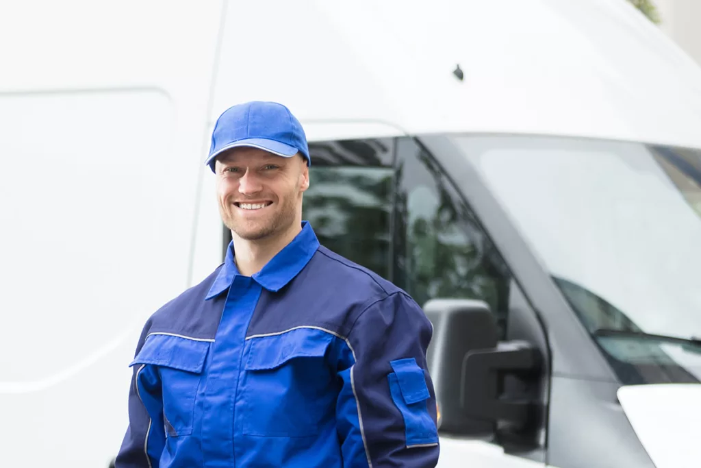 A smiling hot tub maintenance technician in a blue uniform stands in front of a white van