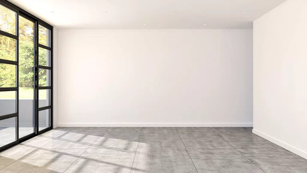 A bright and empty room with gray tiles, white walls, and floor to ceiling windows.