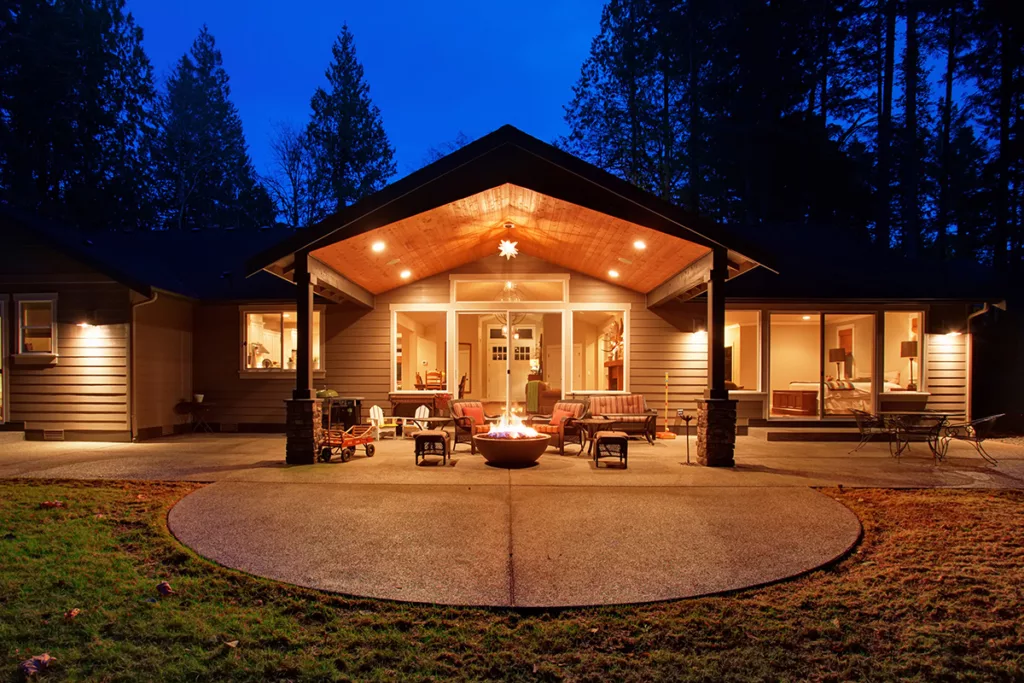 A gas firepit in backyard at night, surrounded by trees.