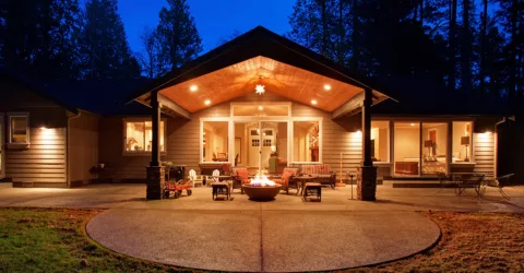 A gas firepit in backyard at night, surrounded by trees.